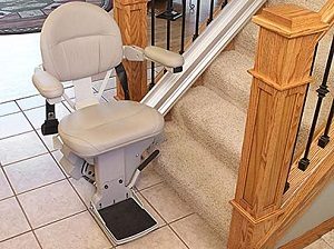 An empty stairlift attached to a carpeted staircase.