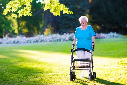 Happy senior using a rollator in a park.