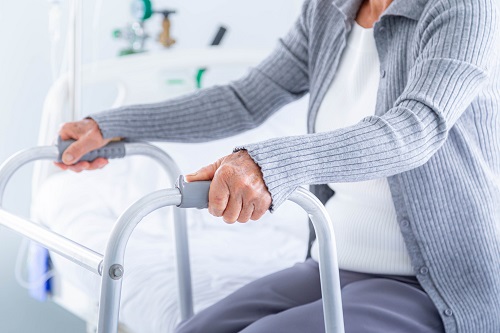 Close-up senior woman using a walker at hospital.
