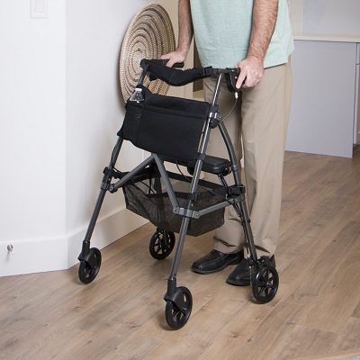 A man using a rollator in a room with hardwood floors.