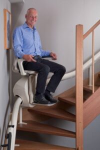 Older man riding a stairlift and smiling