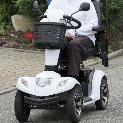 An individual uses a mobility scooter to ride down a residential street.