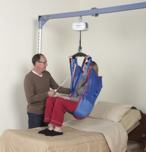 Person being placed in a lift by caregiver to move from bed
