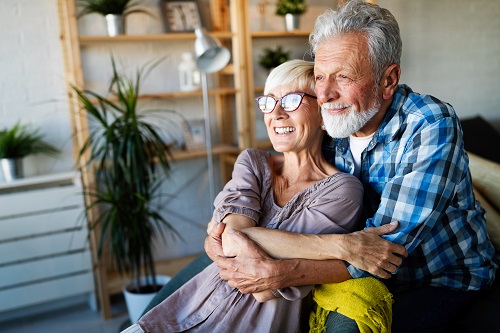 Happy smiling senior couple embracing together at home.