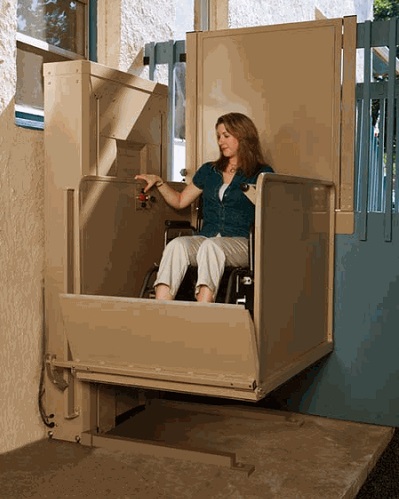Woman in wheelchair using a platform lift on a porch.