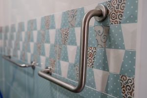 Grab bar installed on a shower wall with blue tile