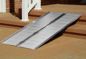 A portable wheelchair ramp on exterior porch stairs.