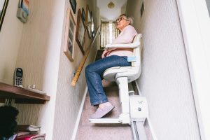 Woman on a stair lift going upstairs in her home