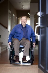 Man in wheelchair exiting home through automatic front door