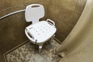 White seat in brown-tiled shower
