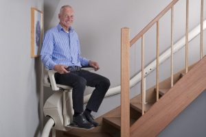 Person sitting on curved stair lift going upstairs